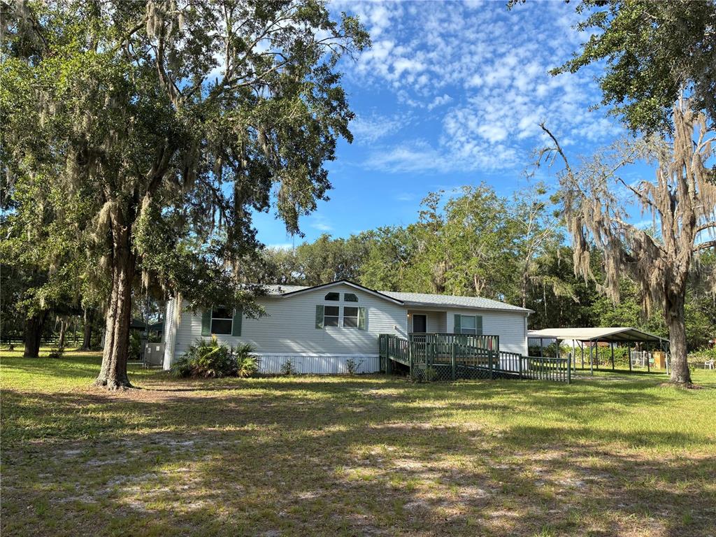 A single-story manufactured home with a wooden deck and ramp sits on a grassy lot — 21919 NE 69TH PLACE, MELROSE, FL
