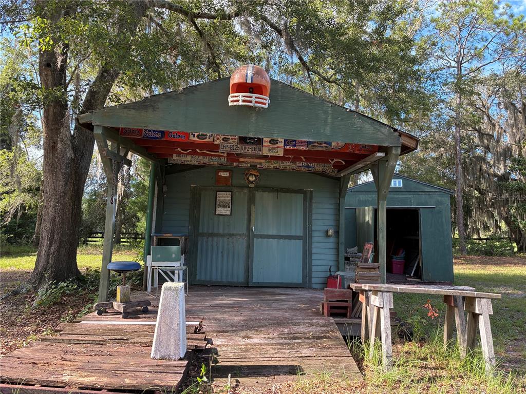 A wooden shed with a covered porch features a football helmet mounted above the entrance — 21919 NE 69TH PLACE, MELROSE, FL