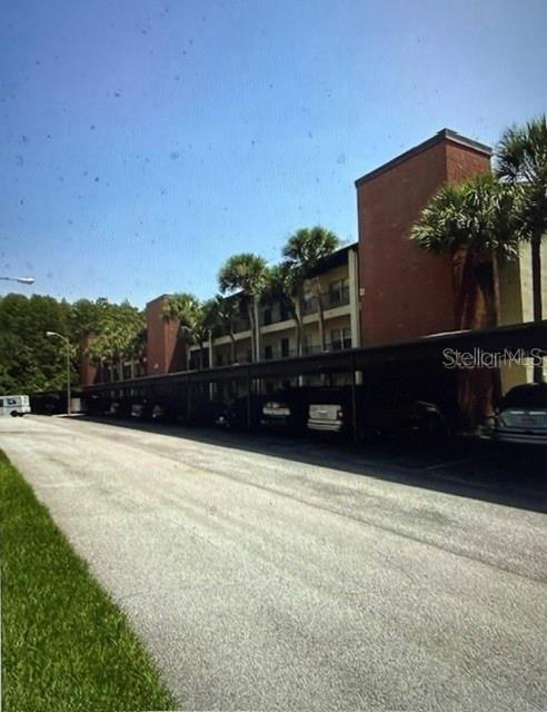 A multi-story apartment building with a covered parking area and palm trees in front — 2438 ENTERPRISE ROAD UNIT 20, CLEARWATER, FL