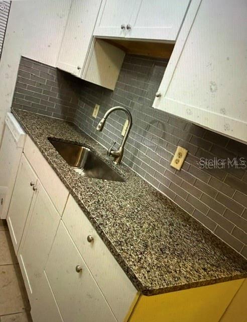 A kitchen features white cabinets, a granite countertop, a stainless steel sink, and gray backsplash — 2438 ENTERPRISE ROAD UNIT 20, CLEARWATER, FL