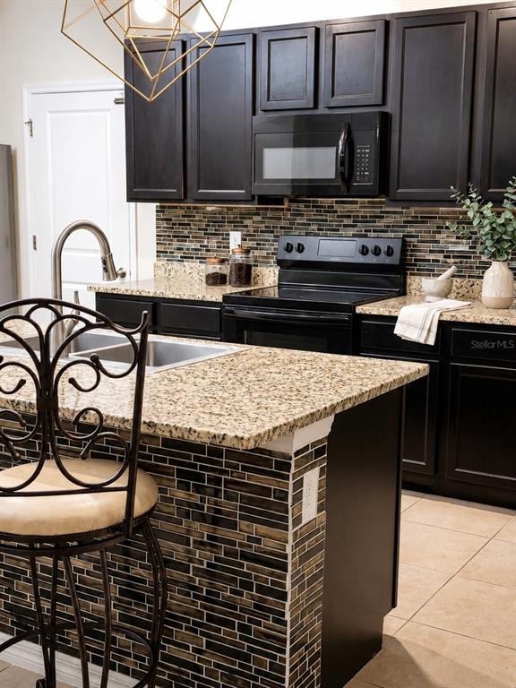 A kitchen features dark cabinets, granite countertops, a tiled island, and a stainless steel faucet — 32649 PEZ LANDING LANE, WESLEY CHAPEL, FL