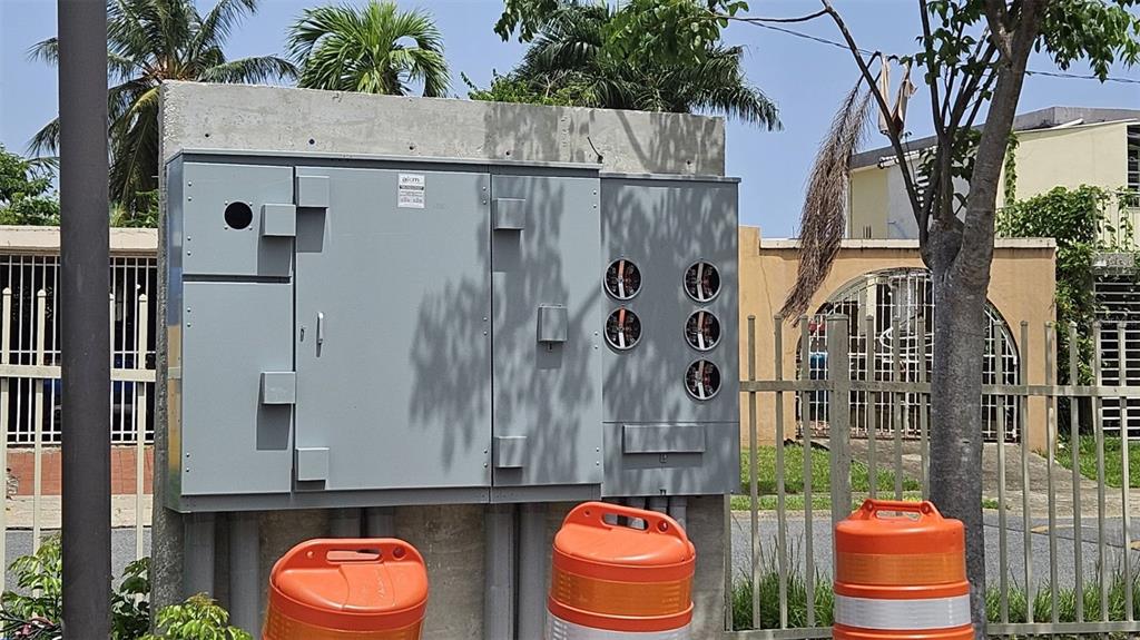 An outdoor electrical panel and meter bank are mounted on a concrete wall near trees — campo AVE. CAMPO RICO INT FIDALGO DIAZ, CAROLINA, PR