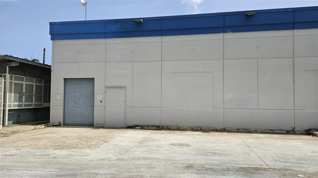 The exterior of a commercial building features a roll-up door, a pedestrian door, and concrete walls — campo AVE. CAMPO RICO INT FIDALGO DIAZ, CAROLINA, PR