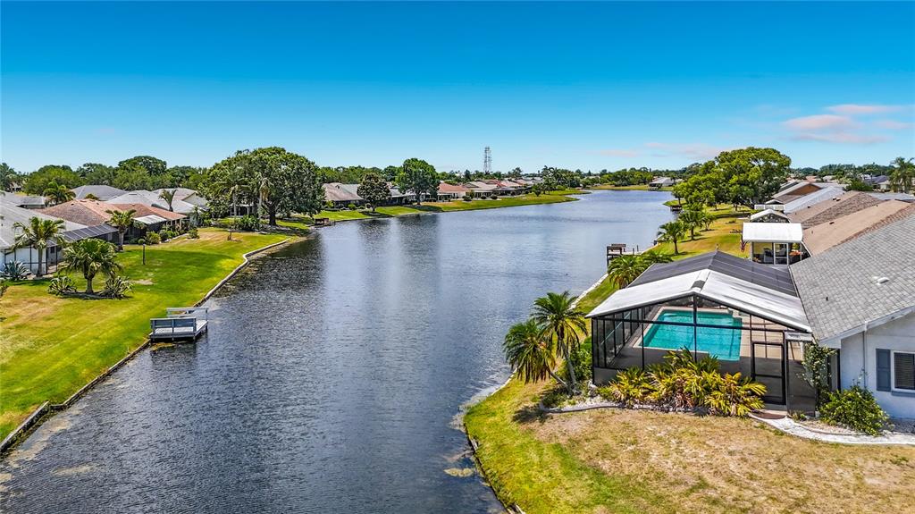 An aerial view shows a canal bordered by houses, including one with a screened pool — 2007 WEDGE COURT, SUN CITY CENTER, FL