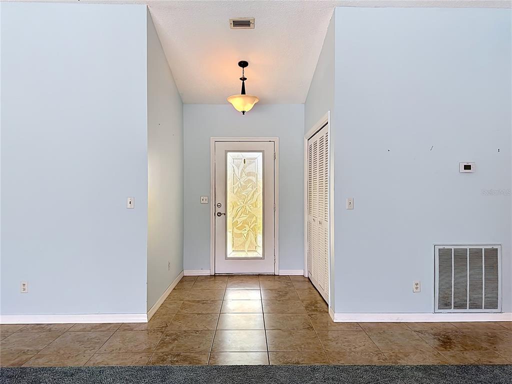 A foyer with light blue walls, tile flooring, a glass-paneled front door, and a pendant light — 2007 WEDGE COURT, SUN CITY CENTER, FL