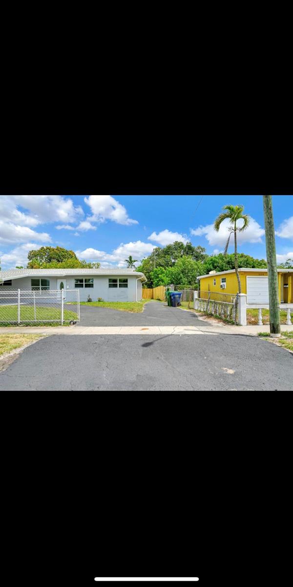 A paved driveway leads to a gray house and a yellow house with a palm tree — 1112 NW 43rd Terrace, Lauderhill FL 33313, LAUDERHILL, FL