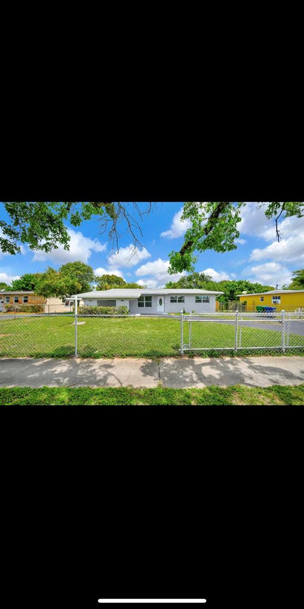 A single-story gray house with a chain-link fence and a large front lawn — 1112 NW 43rd Terrace, Lauderhill FL 33313, LAUDERHILL, FL
