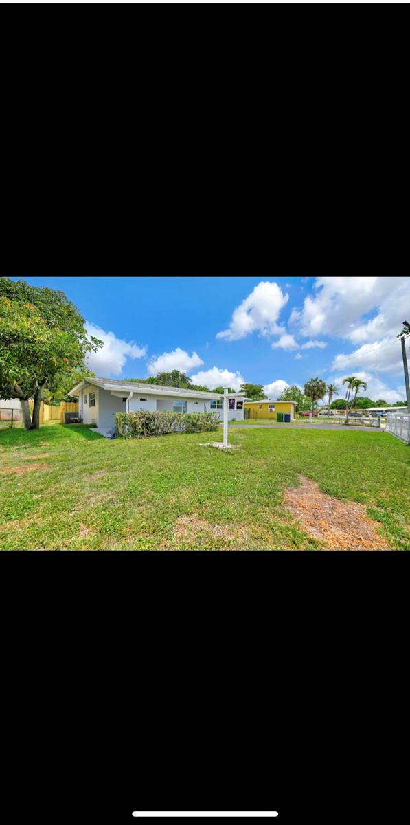 A single-story house with a white exterior sits on a large, grassy residential lot — 1112 NW 43rd Terrace, Lauderhill FL 33313, LAUDERHILL, FL