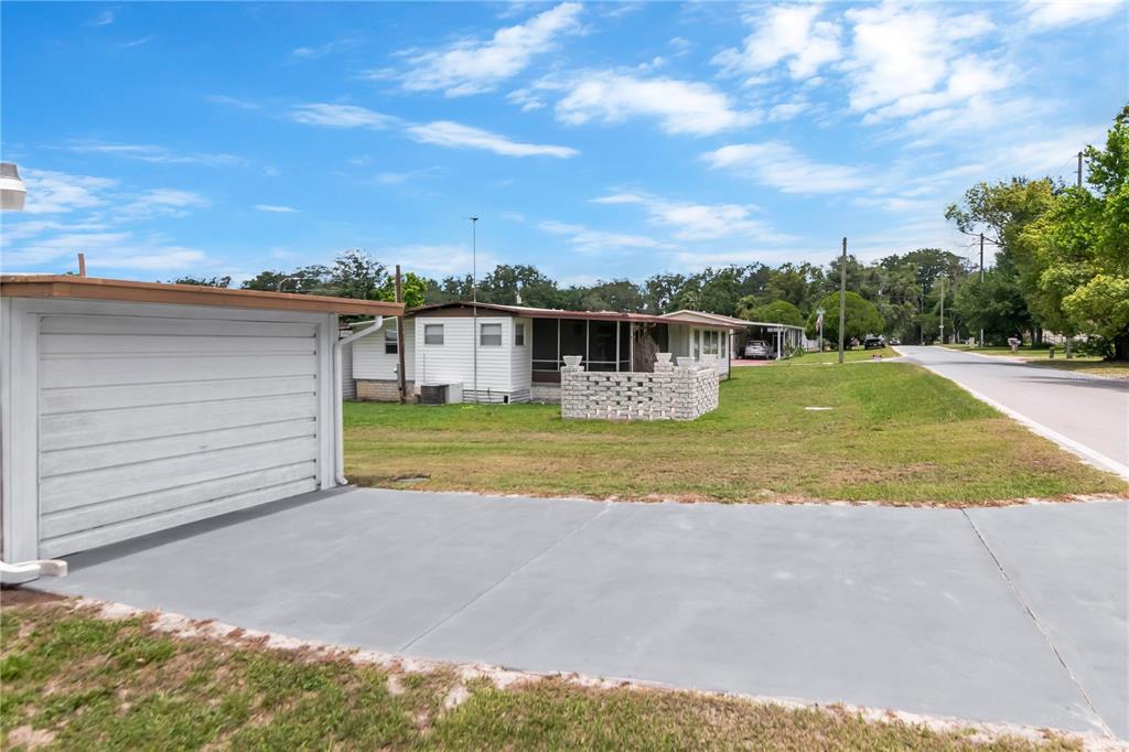 A concrete driveway leads to a detached garage next to a single-story mobile home — 39219 OLA AVENUE, ZEPHYRHILLS, FL