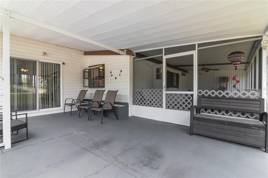 A covered patio features a concrete floor, outdoor seating, and a screened-in porch area — 39219 OLA AVENUE, ZEPHYRHILLS, FL