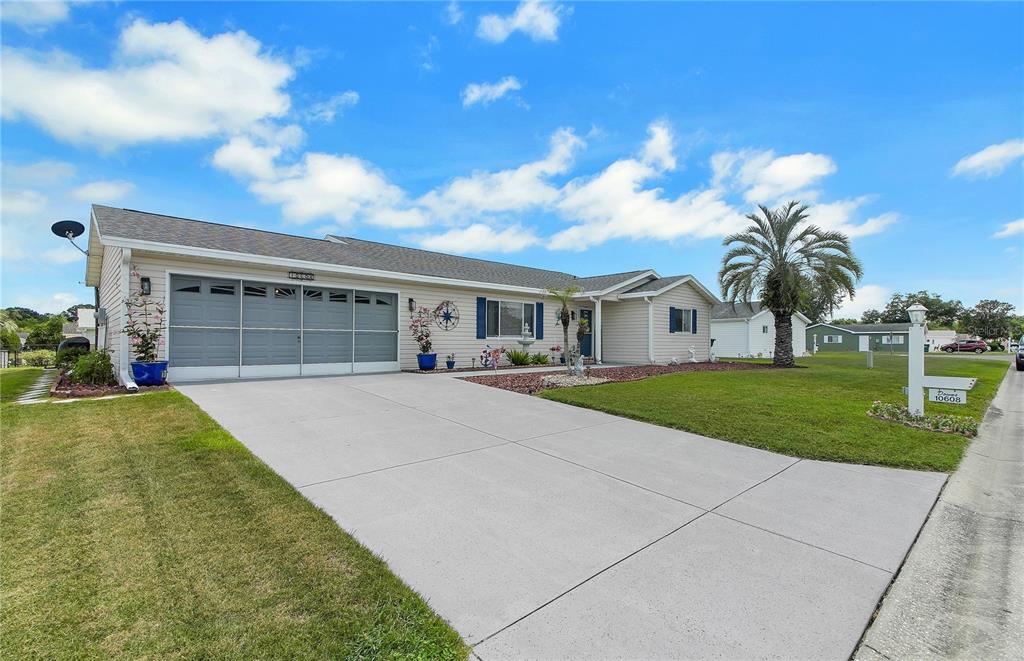 A single-story house with a gray garage door, light siding, and a concrete driveway — 10608 SE 174TH LOOP, SUMMERFIELD, FL