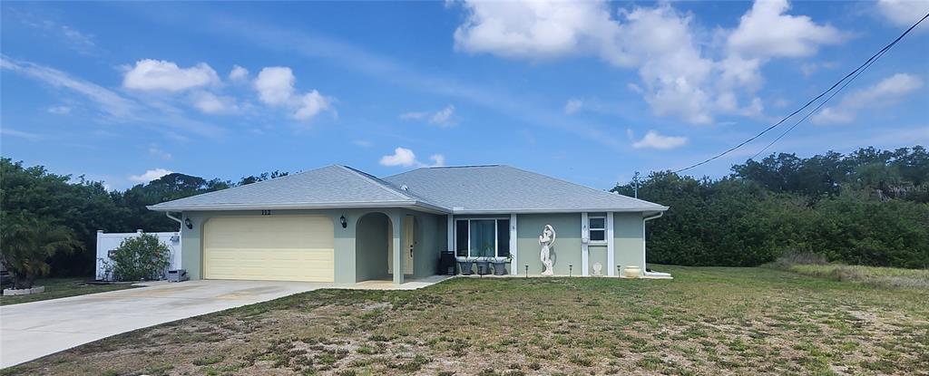 A light green single-story house features a two-car garage and a large front lawn — 112 ANTILLA ROAD, NORTH PORT, FL
