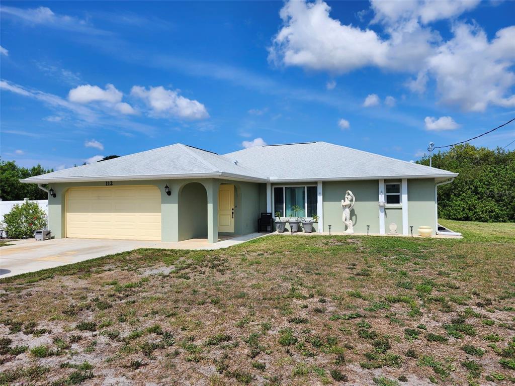 A light green, single-story house with a two-car garage and a light-colored shingled roof — 112 ANTILLA ROAD, NORTH PORT, FL