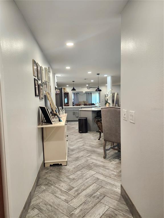 A hallway with herringbone tile flooring leads into an open-concept kitchen with a center island — 112 ANTILLA ROAD, NORTH PORT, FL