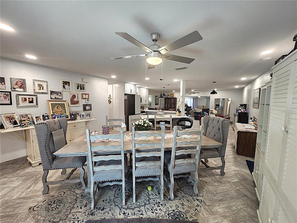 A dining area with a wooden table and upholstered chairs opens into a modern kitchen — 112 ANTILLA ROAD, NORTH PORT, FL