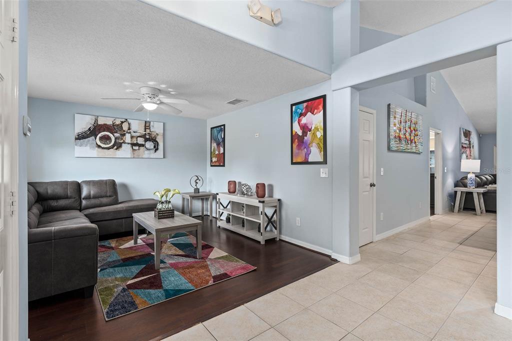 A living room features a grey sectional sofa, a colorful rug, and dark wood flooring — 1030 COVENTRY ROAD, DAVENPORT, FL