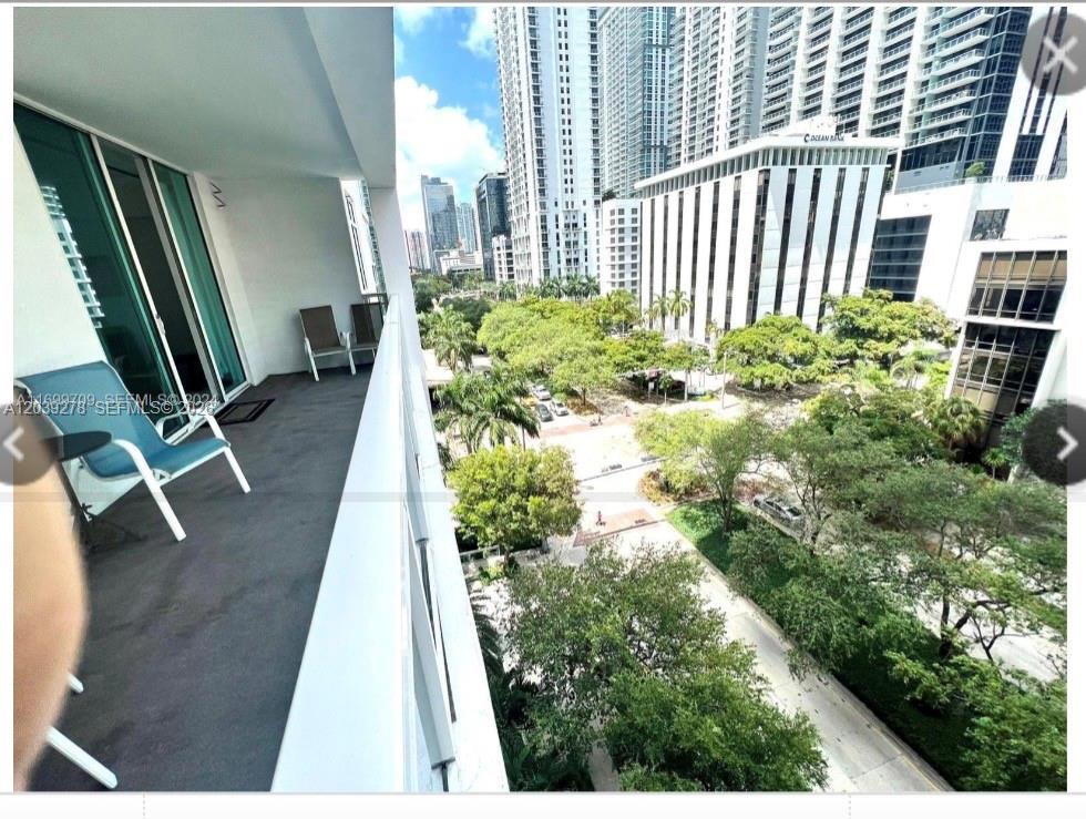 A balcony with chairs overlooks a street lined with trees and tall city buildings — 951 Brickell ave # 709, Miami FL 33131, MIAMI, FL