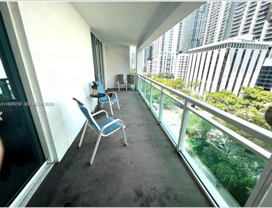 A balcony with outdoor chairs overlooks a city street and high-rise buildings — 951 Brickell ave # 709, Miami FL 33131, MIAMI, FL