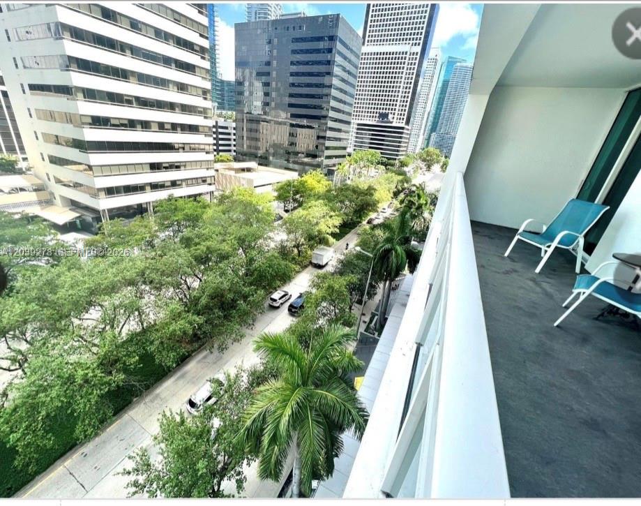A balcony with two blue chairs overlooks a city street lined with trees and buildings — 951 Brickell ave # 709, Miami FL 33131, MIAMI, FL