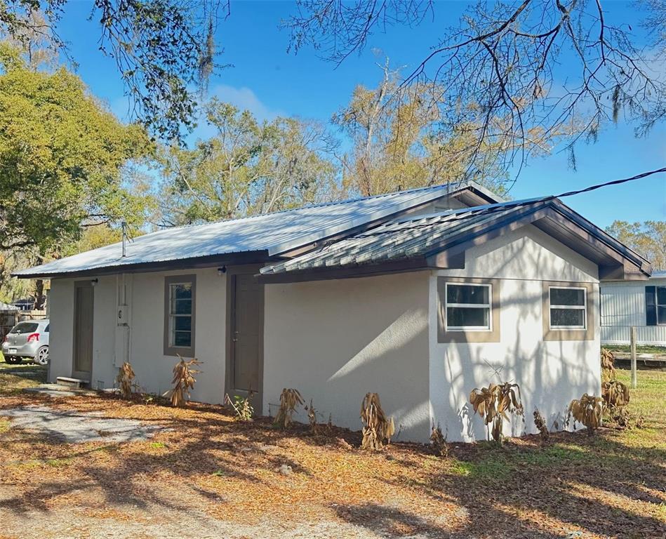 A single-story house with a white metal roof and light-colored stucco exterior — 711 NASHVILLE ROAD, LAKELAND, FL