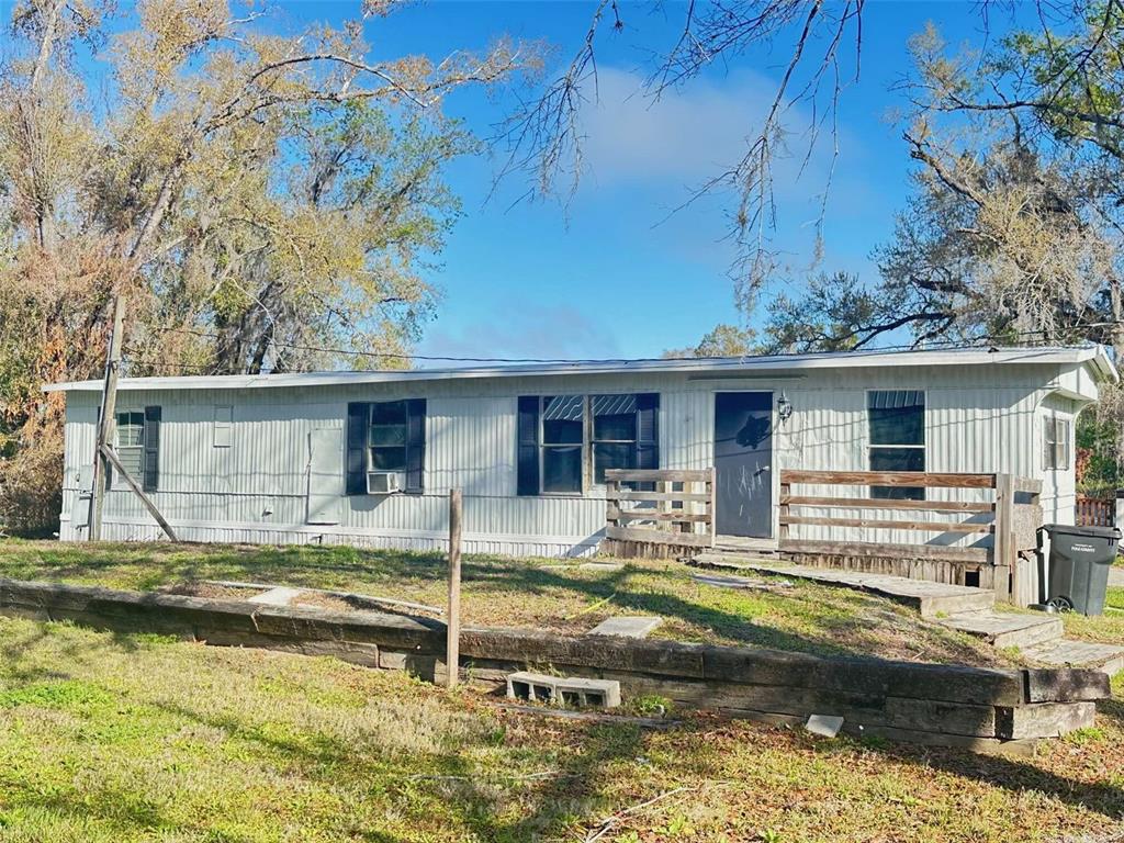 A single-story mobile home with white siding, black shutters, and a wooden front deck — 711 NASHVILLE ROAD, LAKELAND, FL