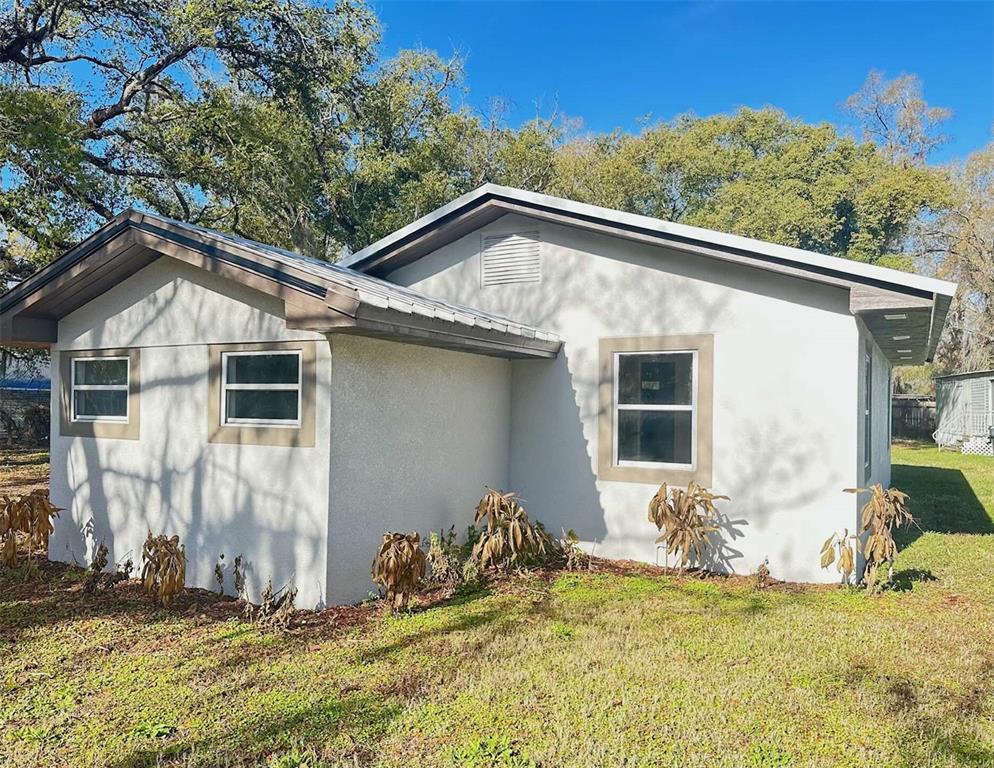 A single-story house with light-colored stucco siding, a metal roof, and several windows — 711 NASHVILLE ROAD, LAKELAND, FL