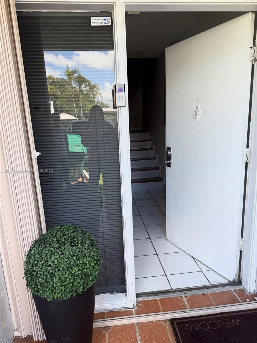 An open white door reveals a tiled entryway leading to a staircase inside a home — 10330 SW 154th Cir Ct # 51, Miami FL 33196, MIAMI, FL