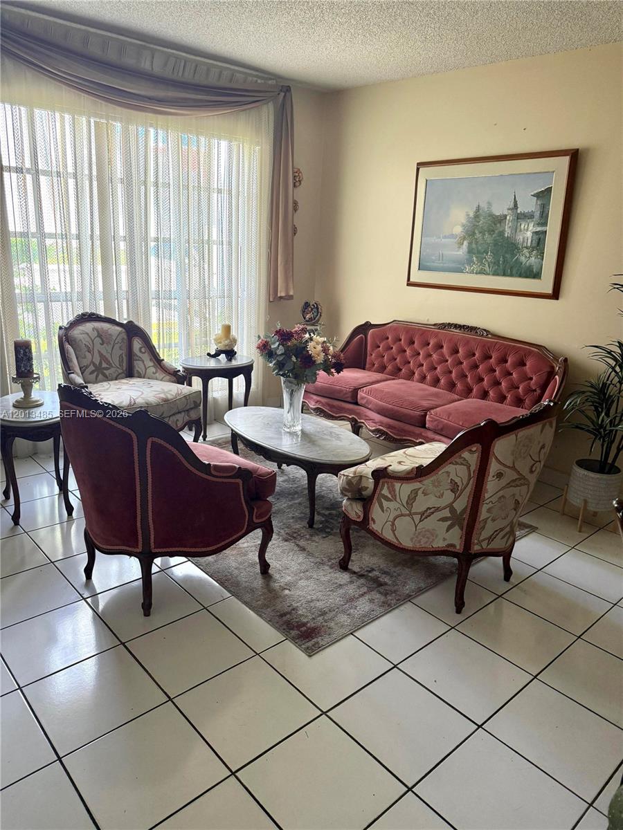 A living room features a tufted red sofa, patterned armchairs, and a central coffee table — 10330 SW 154th Cir Ct # 51, Miami FL 33196, MIAMI, FL