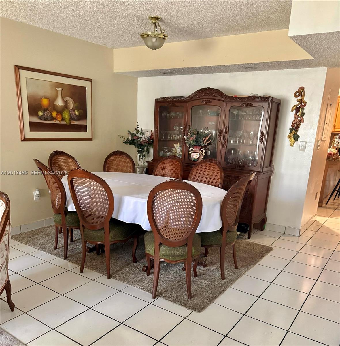 A dining room features a wooden hutch, a table with six cane-back chairs, and tile flooring — 10330 SW 154th Cir Ct # 51, Miami FL 33196, MIAMI, FL