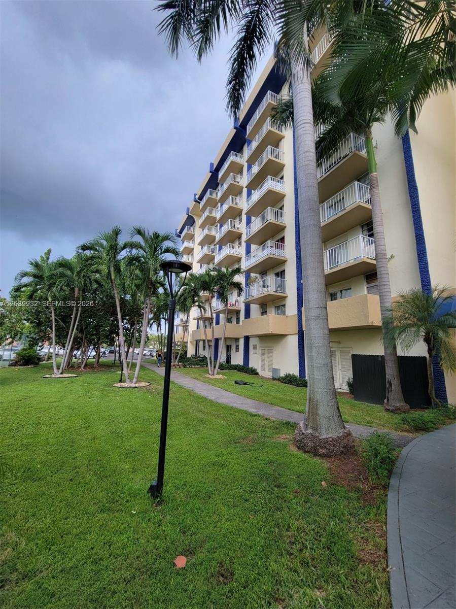 A multi-story apartment building with balconies stands next to a lawn and palm trees — 4550 NW 9th St # 512E, Miami FL 33126, MIAMI, FL