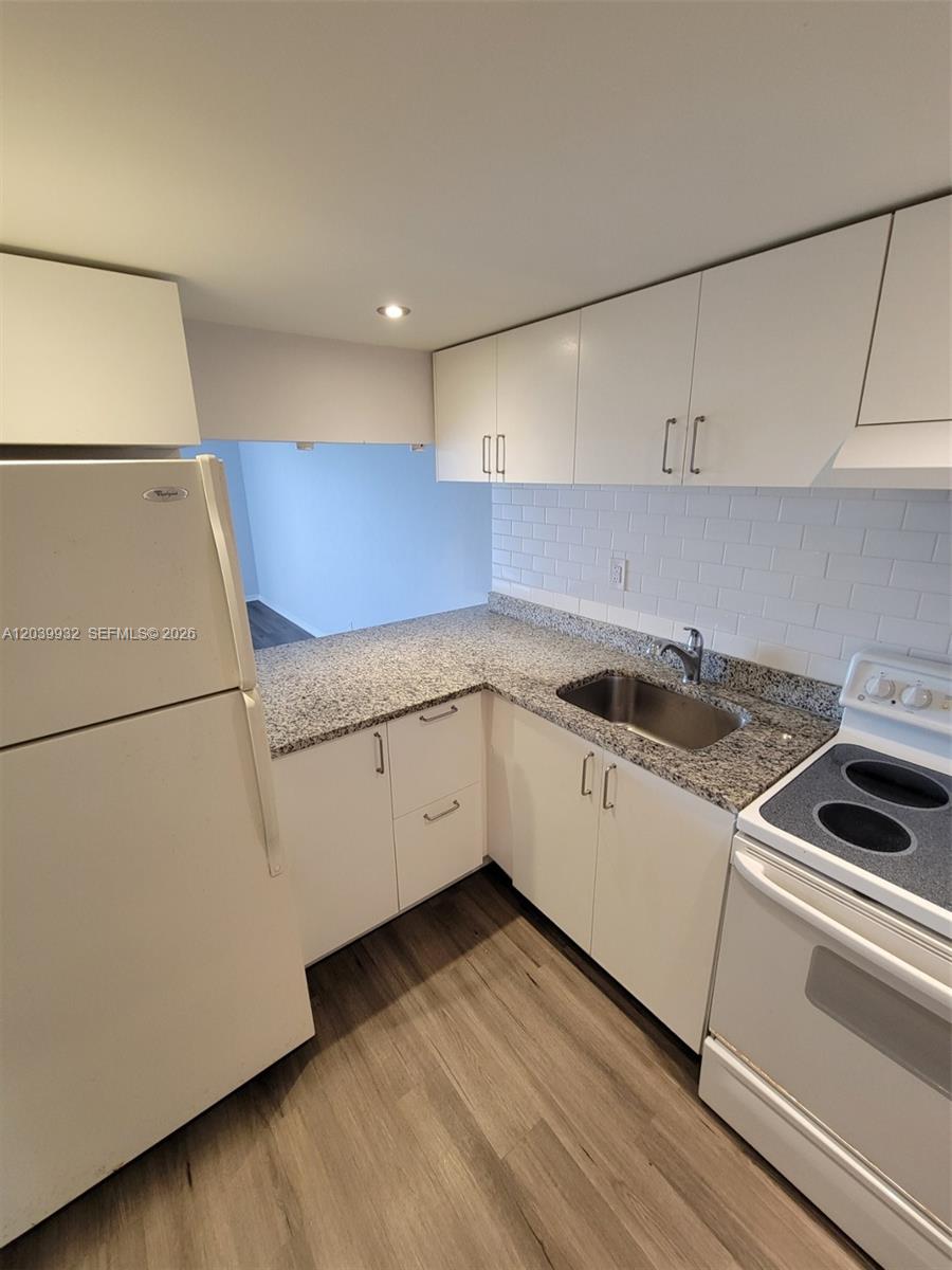 A kitchen features white cabinets, granite countertops, a stainless steel sink, and light wood flooring — 4550 NW 9th St # 512E, Miami FL 33126, MIAMI, FL