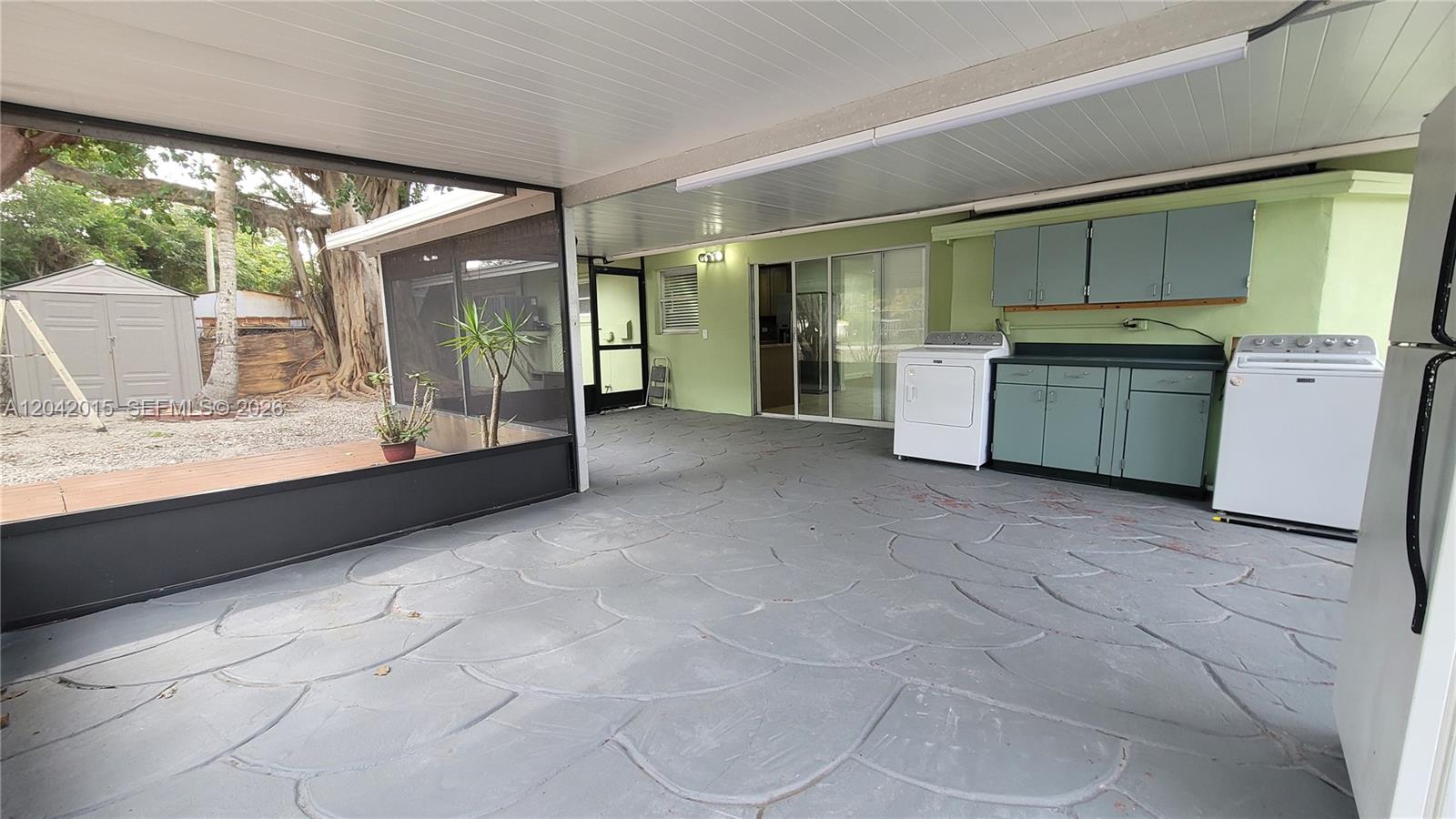 A covered patio features a laundry area with cabinets, appliances, and a patterned concrete floor — 664 Colson Dr, Key Colony FL 33037, KEY COLONY, FL