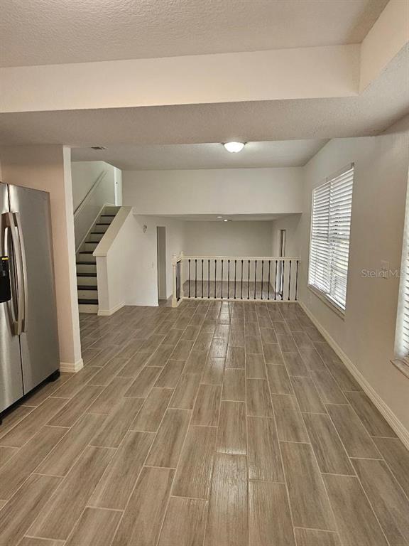 A kitchen area with wood-look tile flooring leads to a sunken living space with railings — 3610 GREENSTONE PLACE, VALRICO, FL