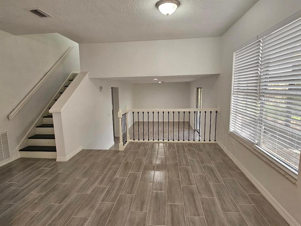 A room with wood-look tile flooring, a staircase, and a balcony overlooking a lower level — 3610 GREENSTONE PLACE, VALRICO, FL