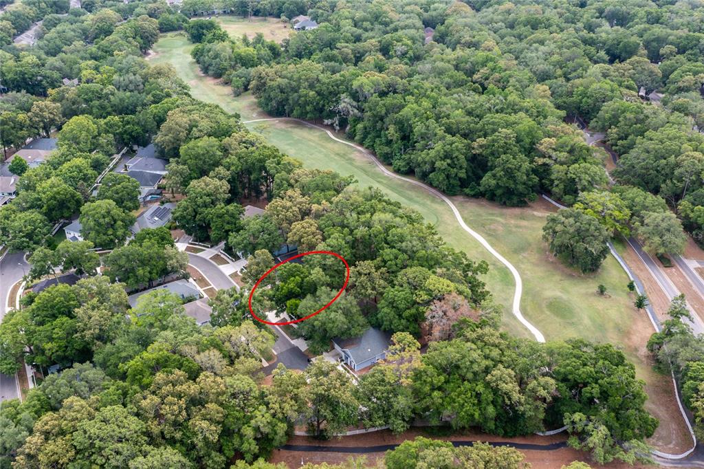 An aerial view shows a wooded residential lot circled in red next to a golf course — 5231 SW 103RD DRIVE, GAINESVILLE, FL