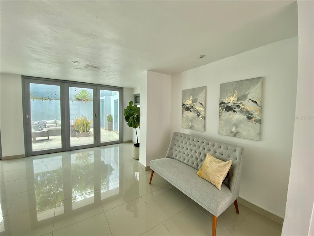 A modern room features a tufted gray settee, two abstract paintings, and glass patio doors — 0 ALHAMBRA, GUAYNABO, PR