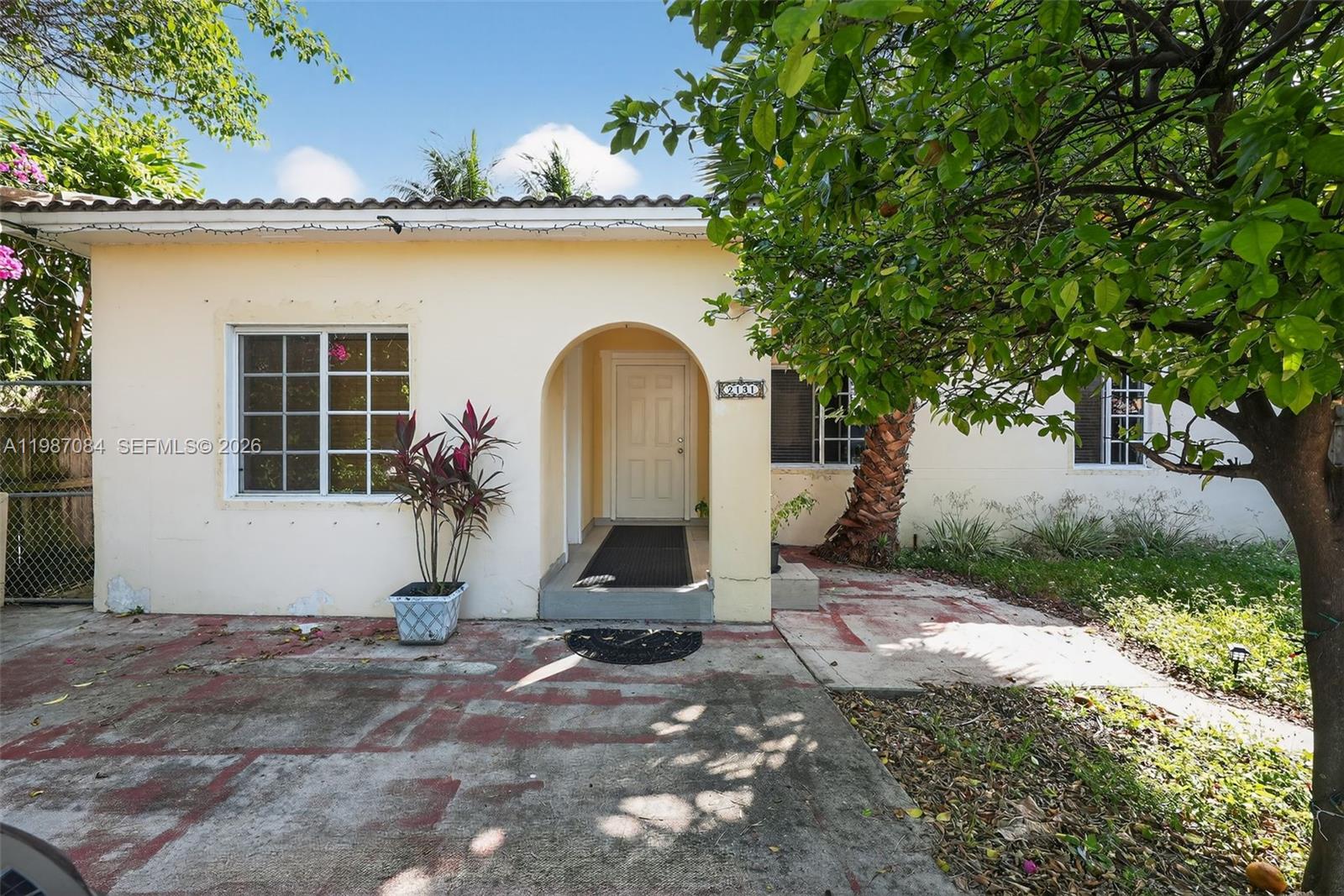 A single-story house with a cream-colored exterior, an arched entryway, and a concrete driveway — 2131 Biarritz Dr, Miami Beach FL 33141, MIAMI BEACH, FL