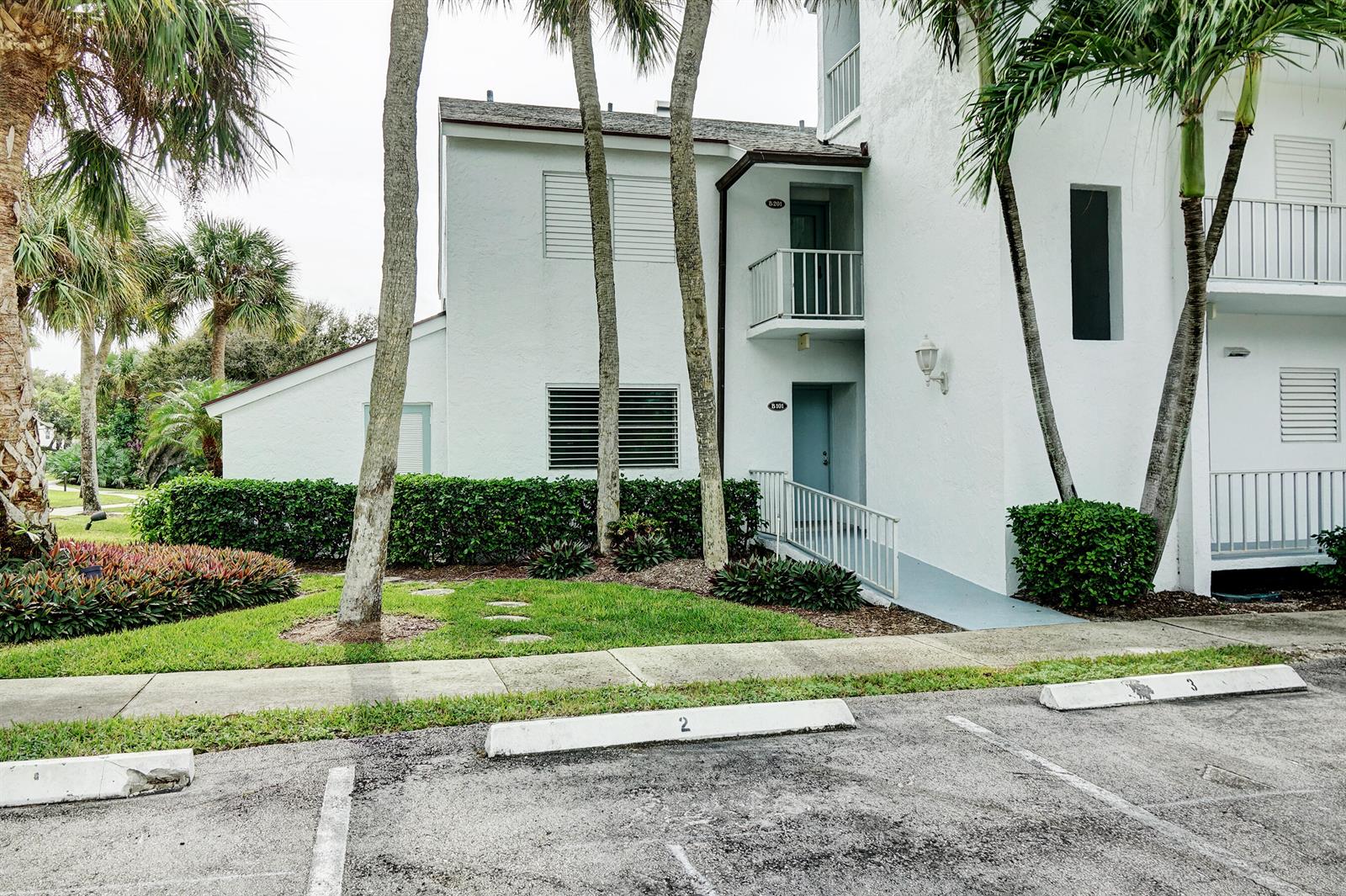 A two-story white apartment building with a ramp entrance and numbered parking spaces in front — 1550 NE Ocean Boulevard # B101, Stuart FL 34996, STUART, FL