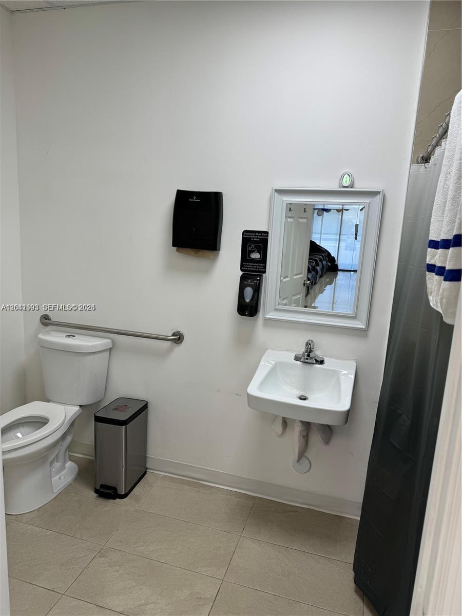 A small bathroom features a white toilet, a wall-mounted sink, and a mirror — 0000 W 20th Ln, Hialeah FL 33016, HIALEAH, FL
