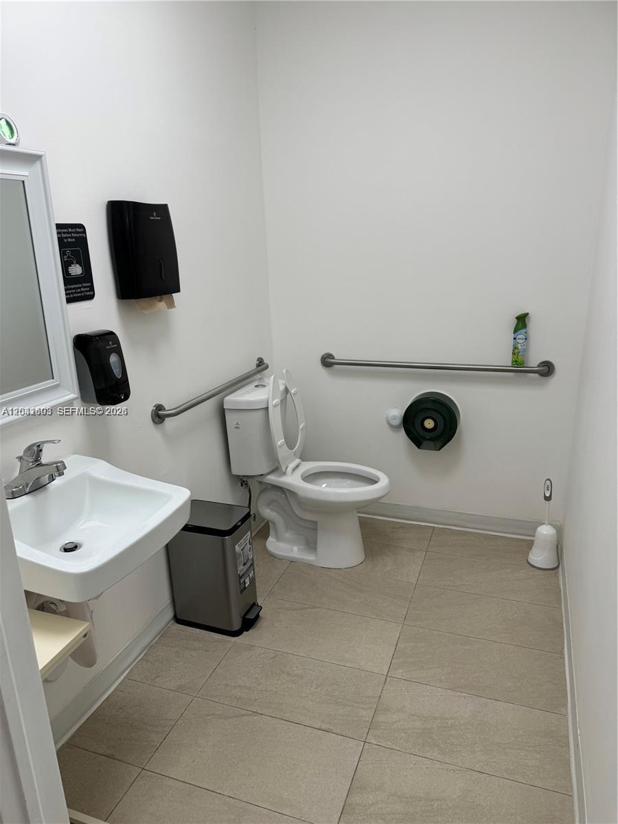 A small, white-walled restroom features a sink, a toilet with grab bars, and tile flooring — 0000 W 20th Ln, Hialeah FL 33016, HIALEAH, FL