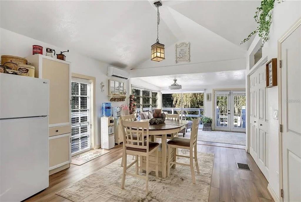 A dining area with a vaulted ceiling, wood floors, and a view into a sunroom — 1192 ERROL PARKWAY, APOPKA, FL