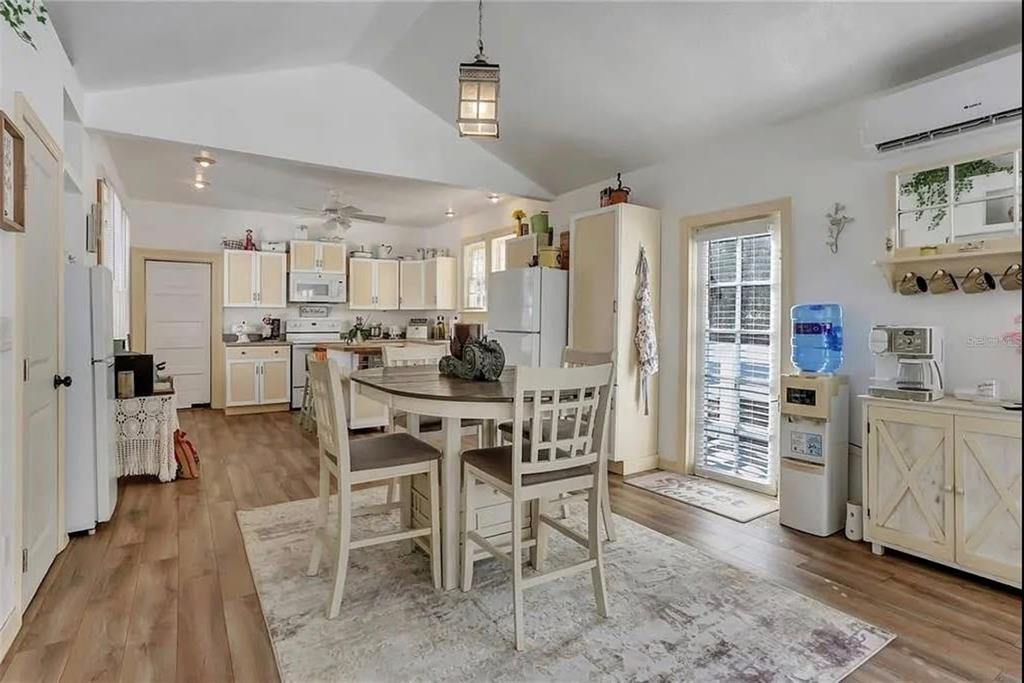 A kitchen and dining area with white cabinets, a round table, and wood-look flooring — 1192 ERROL PARKWAY, APOPKA, FL