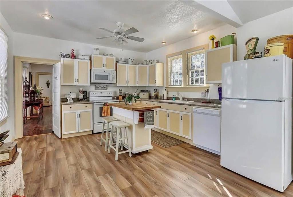 A kitchen with light-colored cabinets, wood-look flooring, a central island, and white appliances — 1192 ERROL PARKWAY, APOPKA, FL