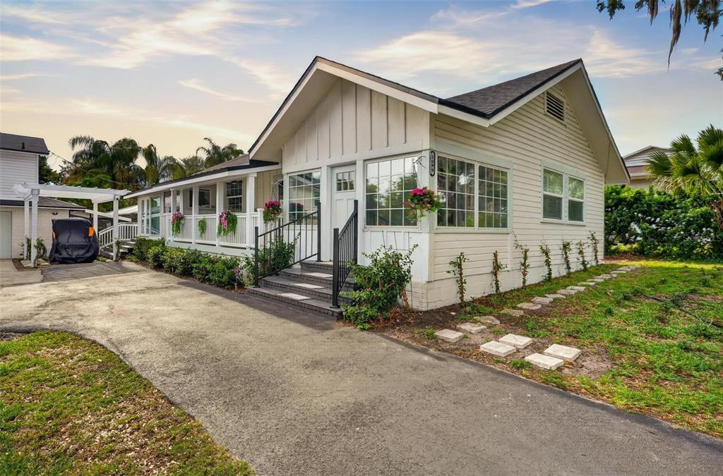 A screened-in porch with wicker furniture overlooks a lake during a vibrant sunset — 1099 GROVE AVENUE, MOUNT DORA, FL