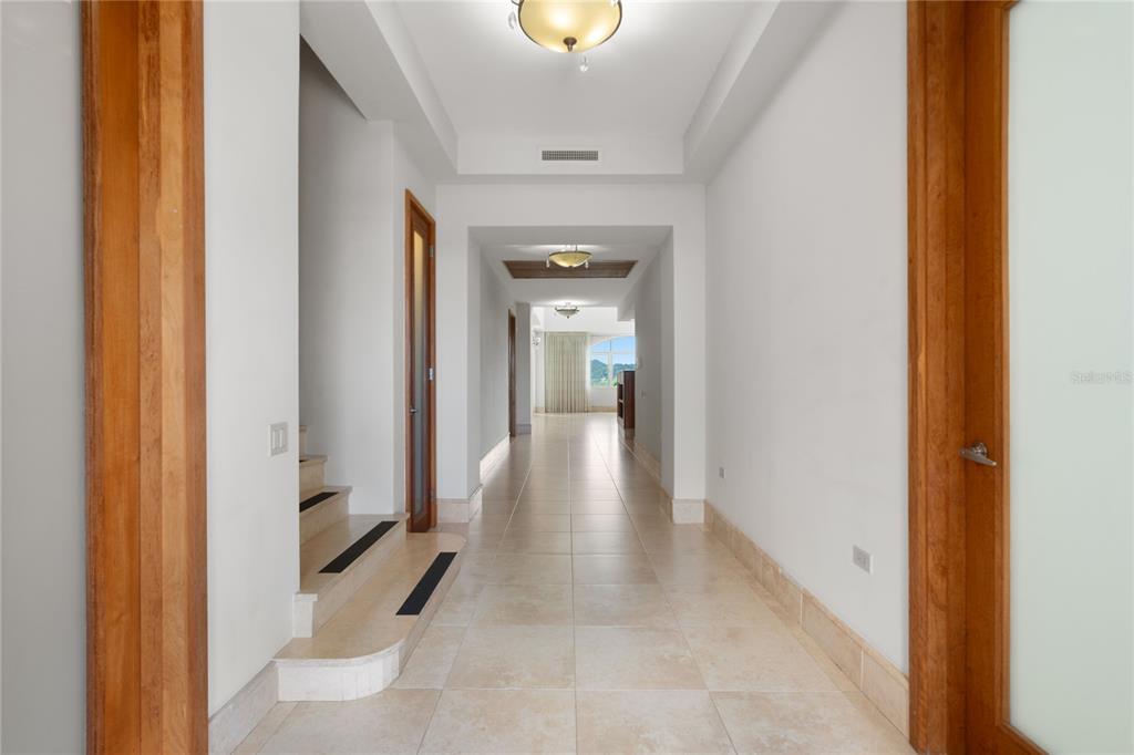 A long hallway with light tile flooring, recessed lighting, and a staircase on the left — 500 PLANTATION VILLAGE DRIVE UNIT PH 2-403, DORADO, PR