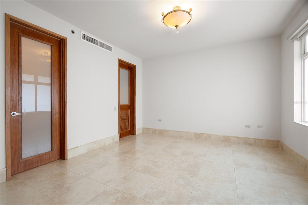 An empty room with light-colored tile flooring, white walls, two wooden doors, and a ceiling light — 500 PLANTATION VILLAGE DRIVE UNIT PH 2-403, DORADO, PR