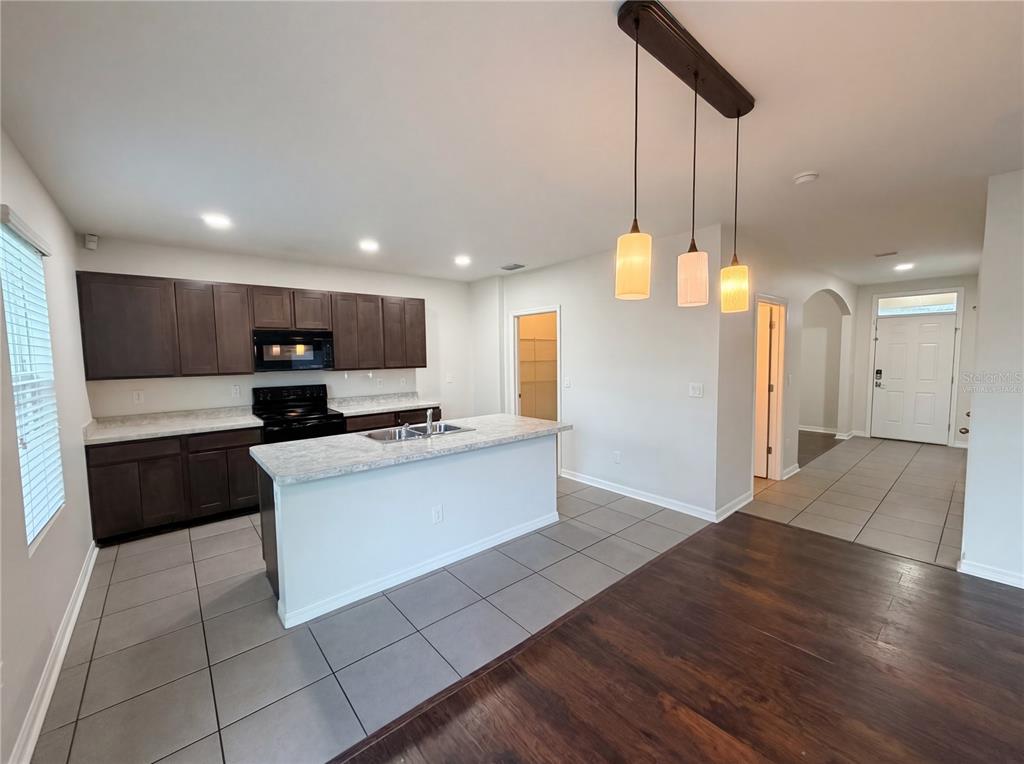 A kitchen with dark wood cabinets, a central island, and tile flooring — 35687 HILLBROOK AVENUE, ZEPHYRHILLS, FL