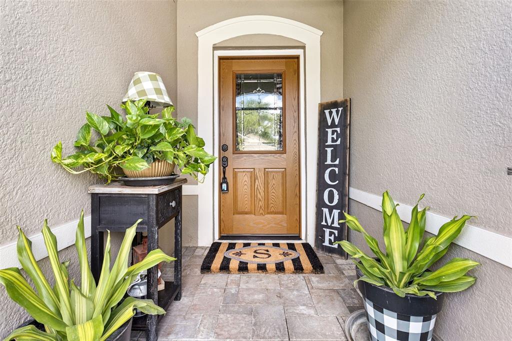 A front entryway features a wooden door, a welcome sign, potted plants, and a small table — 1681 MARSH POINTE DRIVE, CLERMONT, FL