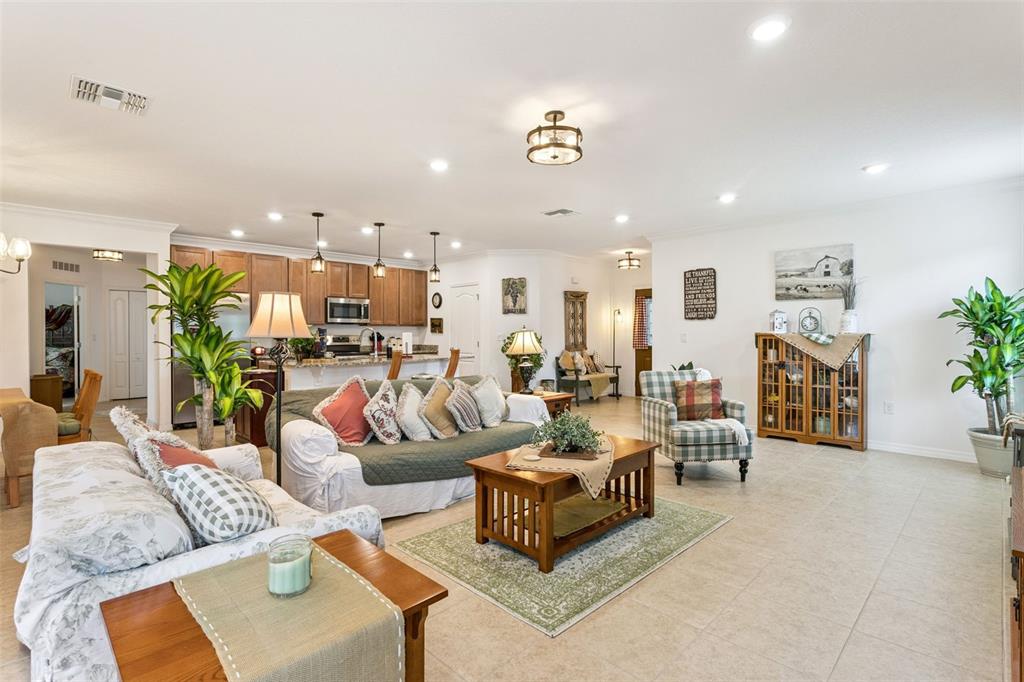 A spacious open-concept living room features tile flooring, a kitchen with wooden cabinets, and furniture — 1681 MARSH POINTE DRIVE, CLERMONT, FL