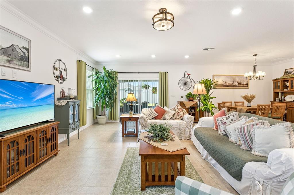 A living room features tile floors, a large television, a sofa, and a dining area — 1681 MARSH POINTE DRIVE, CLERMONT, FL